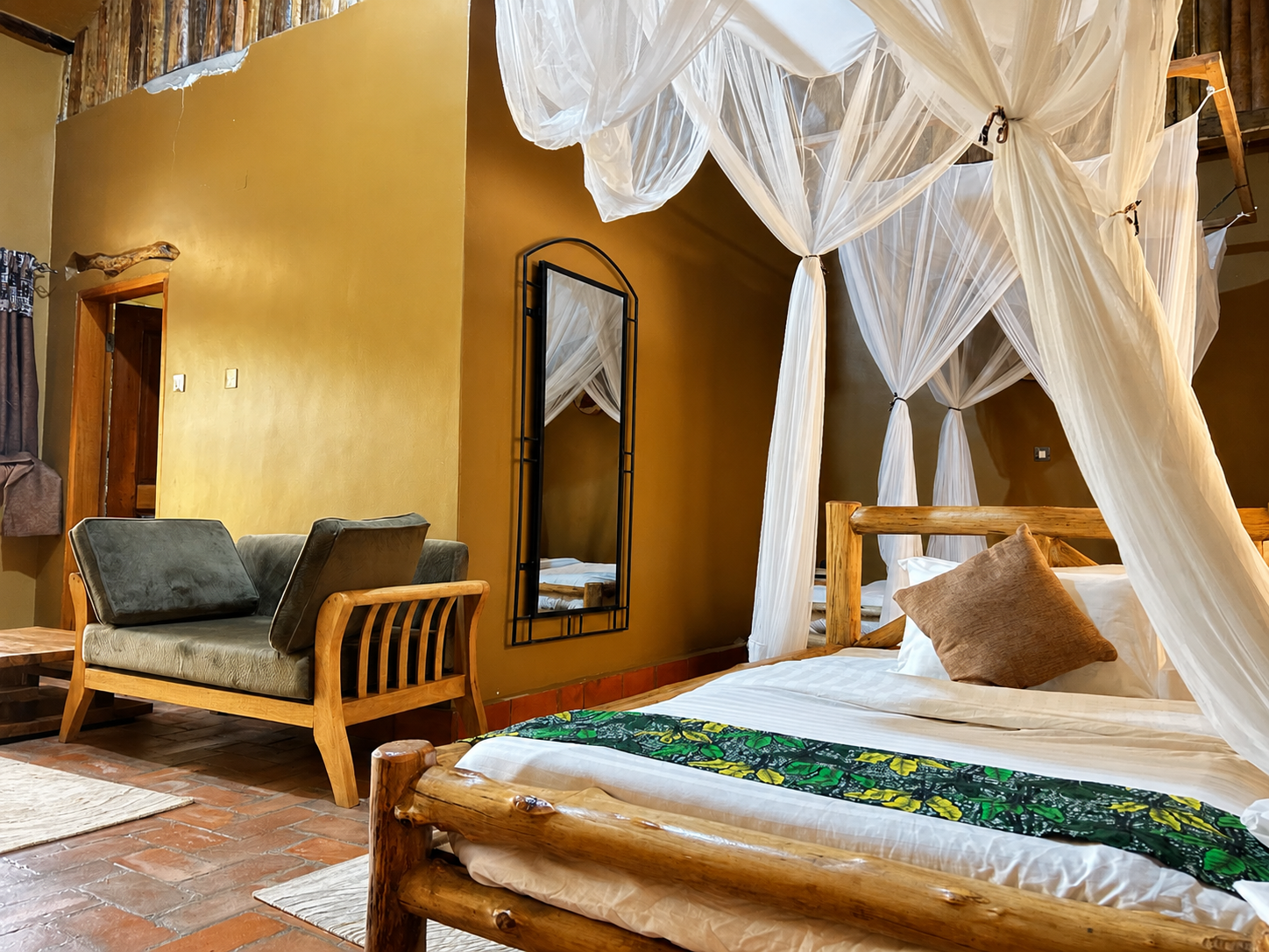 Imhotep banda canopy bed with mirror and lounge view at Warujojo Safari Lodge
