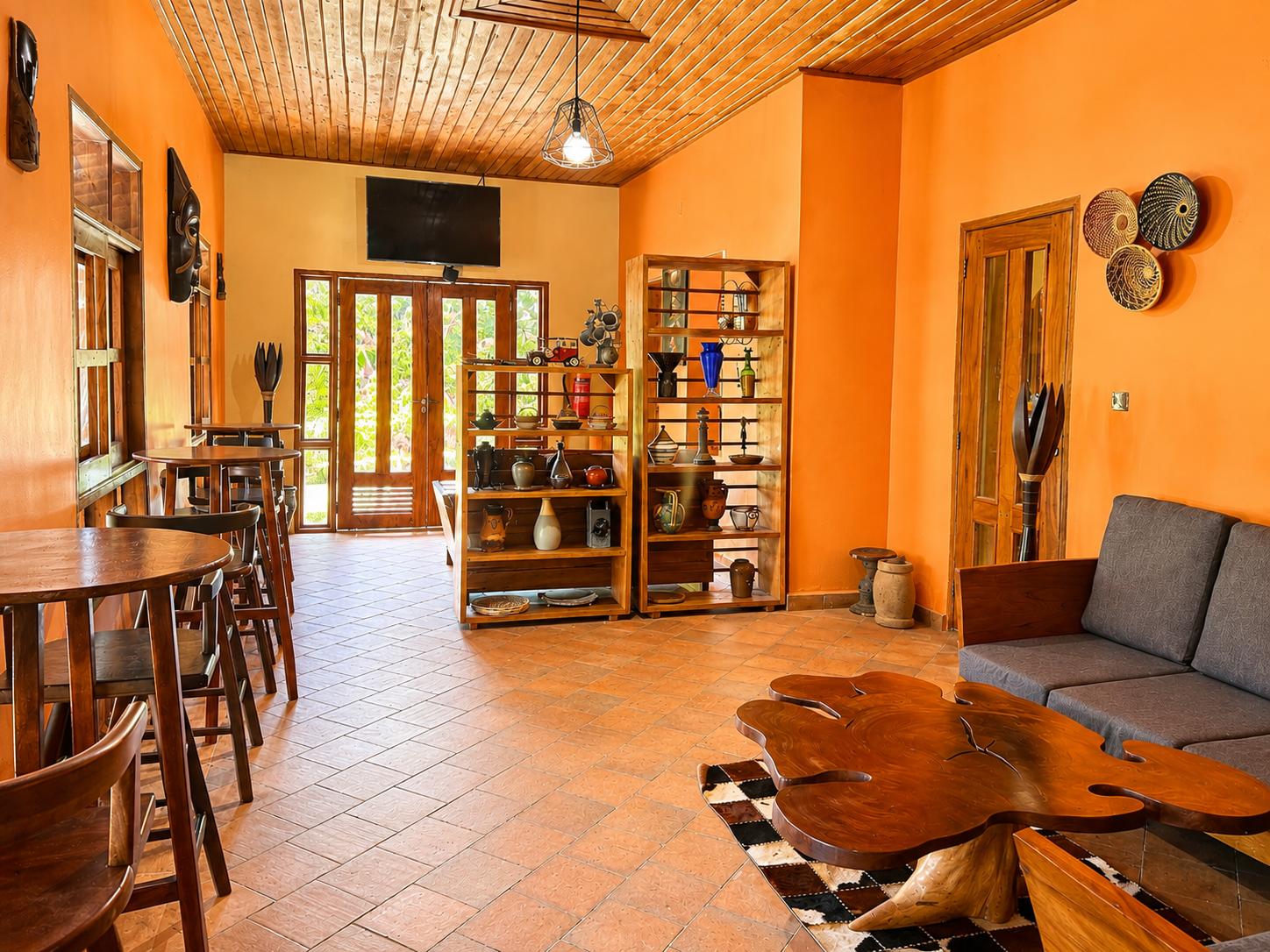 Lounge with charcoal sofas and wildlife art beside the bar at Warujojo Safari Lodge