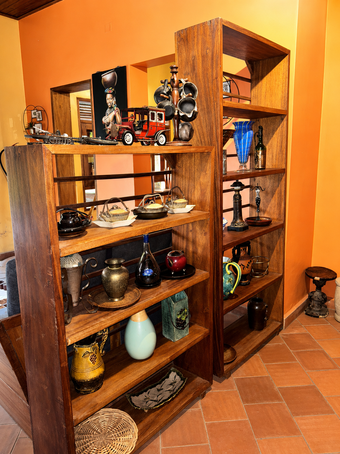 Timber shelves of pottery, gourds and carved artefacts in the bar at Warujojo Safari Lodge