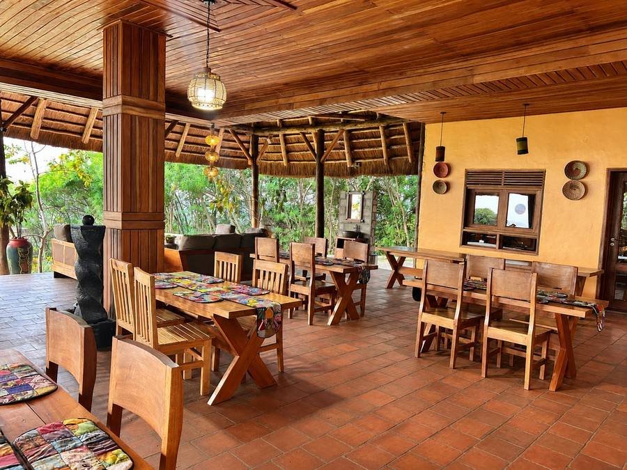 Main dining hall with long timber tables under a high wooden ceiling at Warujojo Safari Lodge