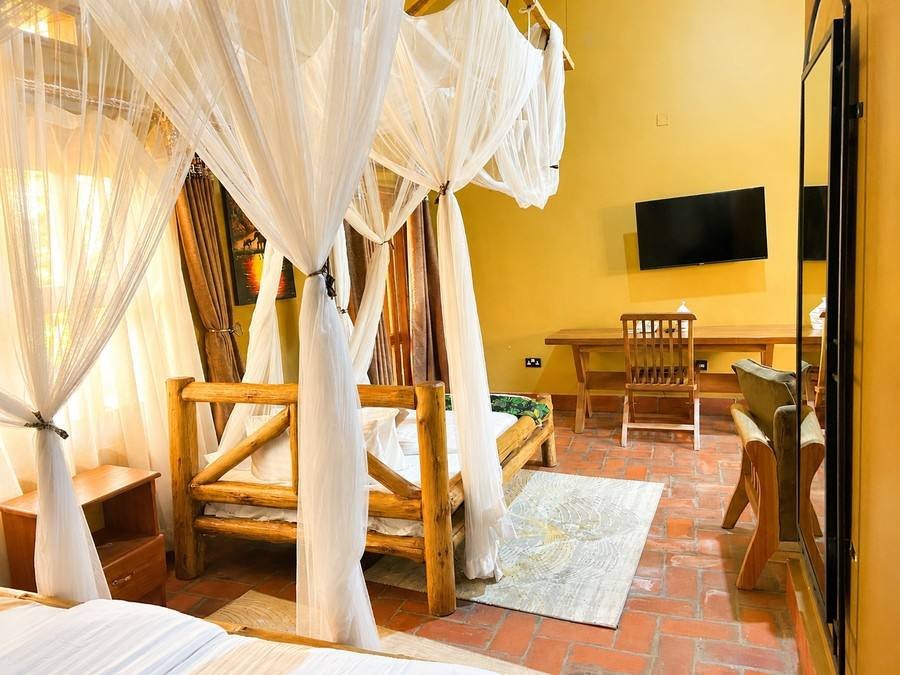 Imhotep banda at Warujojo Safari Lodge: log-framed four-poster bed under a canopy net