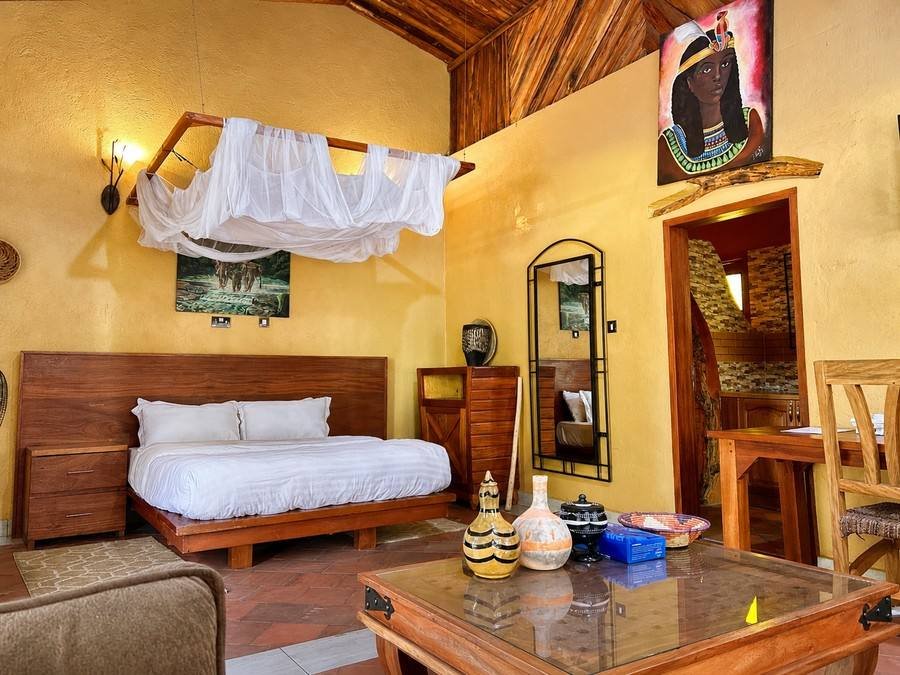 Karakara banda at Warujojo Safari Lodge: platform king bed against golden walls