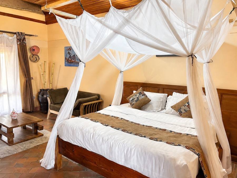 Kibalama cottage at Warujojo Safari Lodge: canopied king bed on a terracotta-tile floor
