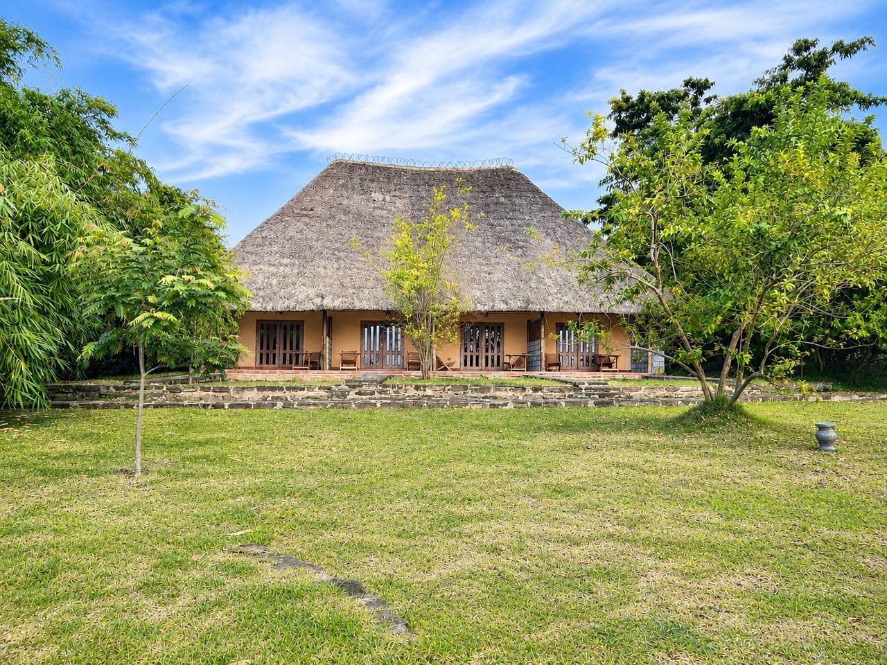 Thatched bandas across the lawn at Warujojo Safari Lodge, Kyambura Game Reserve, Uganda