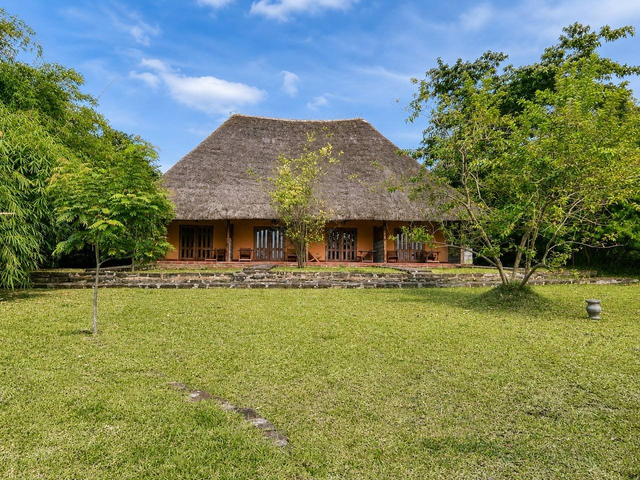Lawns and thatched buildings at Warujojo Safari Lodge glowing in the evening light