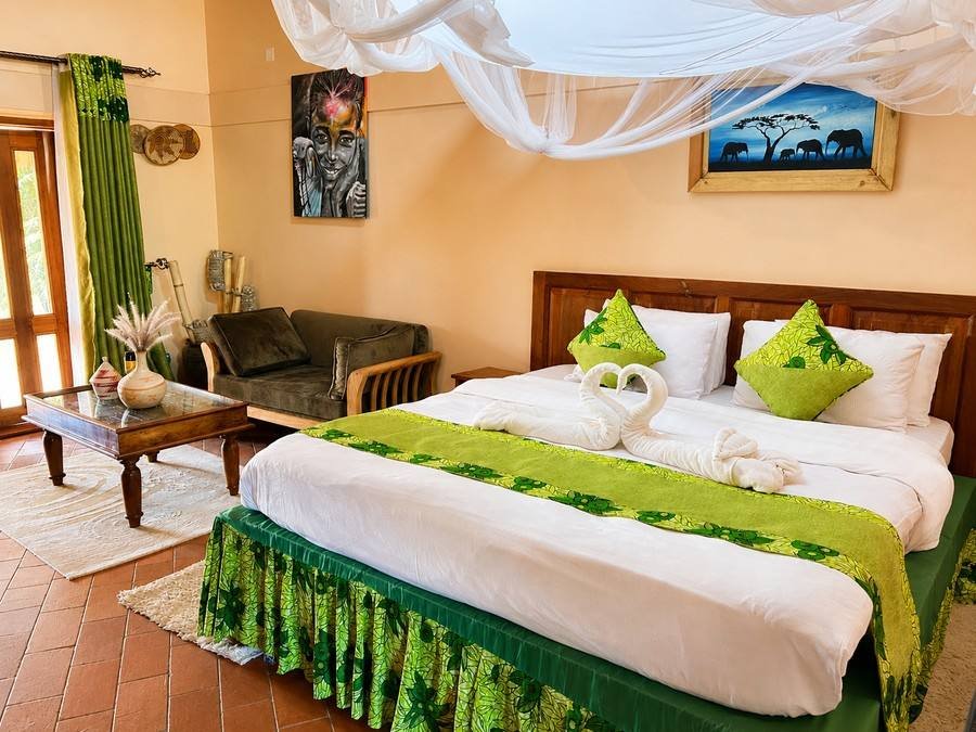 Menelik cottage at Warujojo Safari Lodge: king bed dressed in olive-green African prints