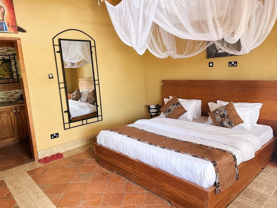 Saraunya banda: mustard-yellow walls and a four-poster bed under a white mosquito-net canopy